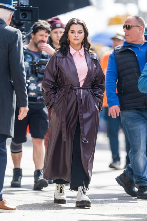 Selena Gomez On The Set in NYC - March 17 2023

Selena Gomez - ''Only Murderers in the Building'' set, NYC - March 17, 2023

Selena Gomez Wears Chic Oversized Plum Coat On 'Only Murders In the Building' Set

On Friday morning, Selena Gomez was photographed on the set of her hit Hulu show Only Murders In The Building in Queens, NY, with her co-stars Steve Martin and Martin Short. The singer and actress' look for the day included black denim pants peeking out from under an oversized dark purple trench coat by Olēnich. The statement piece made from faux leather featured large lapels and a belt cinching her in at the waist.

Under the coat was a pale pink button down and on her feet were a pair of white lace-up boots with a thick black sole.

Gomez left her long brunette hair down in waves and wore a pair of gold double hoop earrings. She had on a natural makeup palette for the shoot with a light coral lip.

On Only Murders in the Building, Gomez plays Mabel Mora, one of a trio of friends who are obsessed with true crime and who start a podcast together as they investigate a murder in their own apartment building. The show was renewed for a third season after receiving much critical acclaim, and has attracted lots of big guest stars like Tina Fey, Ryan Broussard, Jane Lynch, Meryl Streep, Ashley Park, and Paul Rudd.

The pop star told Deadline in an interview last year that when she was pitched the role, she was immediately excited to work with Martin and Short — and that the show's subject was of personal interest to her.

“They pitched me the idea and it led into a whole conversation about my actual obsession with true crime,” said Gomez. “I had just come back from CrimeCon when I had the call and it just felt like it was something I really wanted to do. They were all so lovely. And working with Steve and Marty would be a dream.”

ELLE/AIMÉE LUTKIN