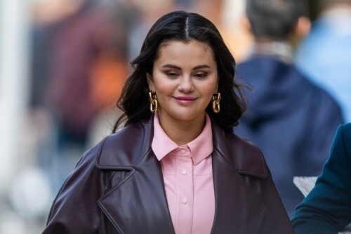 Selena Gomez On The Set in NYC - March 17 2023

Selena Gomez - ''Only Murderers in the Building'' set, NYC - March 17, 2023

Selena Gomez Wears Chic Oversized Plum Coat On 'Only Murders In the Building' Set

On Friday morning, Selena Gomez was photographed on the set of her hit Hulu show Only Murders In The Building in Queens, NY, with her co-stars Steve Martin and Martin Short. The singer and actress' look for the day included black denim pants peeking out from under an oversized dark purple trench coat by Olēnich. The statement piece made from faux leather featured large lapels and a belt cinching her in at the waist.

Under the coat was a pale pink button down and on her feet were a pair of white lace-up boots with a thick black sole.

Gomez left her long brunette hair down in waves and wore a pair of gold double hoop earrings. She had on a natural makeup palette for the shoot with a light coral lip.

On Only Murders in the Building, Gomez plays Mabel Mora, one of a trio of friends who are obsessed with true crime and who start a podcast together as they investigate a murder in their own apartment building. The show was renewed for a third season after receiving much critical acclaim, and has attracted lots of big guest stars like Tina Fey, Ryan Broussard, Jane Lynch, Meryl Streep, Ashley Park, and Paul Rudd.

The pop star told Deadline in an interview last year that when she was pitched the role, she was immediately excited to work with Martin and Short — and that the show's subject was of personal interest to her.

“They pitched me the idea and it led into a whole conversation about my actual obsession with true crime,” said Gomez. “I had just come back from CrimeCon when I had the call and it just felt like it was something I really wanted to do. They were all so lovely. And working with Steve and Marty would be a dream.”

ELLE/AIMÉE LUTKIN