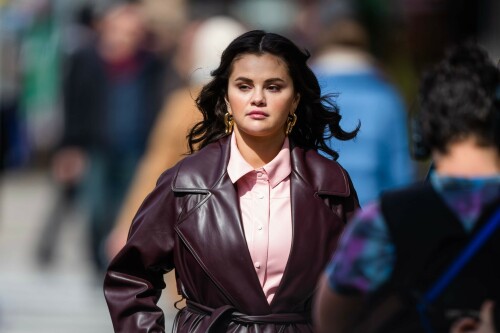 Selena Gomez On The Set in NYC - March 17 2023

Selena Gomez - ''Only Murderers in the Building'' set, NYC - March 17, 2023

Selena Gomez Wears Chic Oversized Plum Coat On 'Only Murders In the Building' Set

On Friday morning, Selena Gomez was photographed on the set of her hit Hulu show Only Murders In The Building in Queens, NY, with her co-stars Steve Martin and Martin Short. The singer and actress' look for the day included black denim pants peeking out from under an oversized dark purple trench coat by Olēnich. The statement piece made from faux leather featured large lapels and a belt cinching her in at the waist.

Under the coat was a pale pink button down and on her feet were a pair of white lace-up boots with a thick black sole.

Gomez left her long brunette hair down in waves and wore a pair of gold double hoop earrings. She had on a natural makeup palette for the shoot with a light coral lip.

On Only Murders in the Building, Gomez plays Mabel Mora, one of a trio of friends who are obsessed with true crime and who start a podcast together as they investigate a murder in their own apartment building. The show was renewed for a third season after receiving much critical acclaim, and has attracted lots of big guest stars like Tina Fey, Ryan Broussard, Jane Lynch, Meryl Streep, Ashley Park, and Paul Rudd.

The pop star told Deadline in an interview last year that when she was pitched the role, she was immediately excited to work with Martin and Short — and that the show's subject was of personal interest to her.

“They pitched me the idea and it led into a whole conversation about my actual obsession with true crime,” said Gomez. “I had just come back from CrimeCon when I had the call and it just felt like it was something I really wanted to do. They were all so lovely. And working with Steve and Marty would be a dream.”

ELLE/AIMÉE LUTKIN