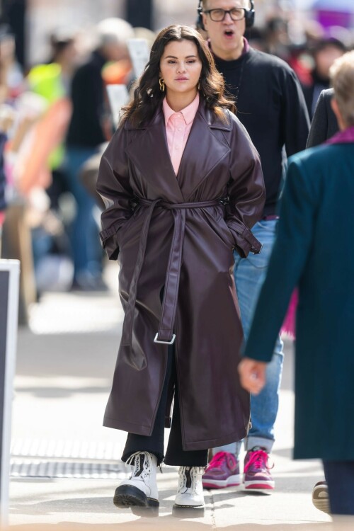 Selena Gomez On The Set in NYC - March 17 2023

Selena Gomez - ''Only Murderers in the Building'' set, NYC - March 17, 2023

Selena Gomez Wears Chic Oversized Plum Coat On 'Only Murders In the Building' Set

On Friday morning, Selena Gomez was photographed on the set of her hit Hulu show Only Murders In The Building in Queens, NY, with her co-stars Steve Martin and Martin Short. The singer and actress' look for the day included black denim pants peeking out from under an oversized dark purple trench coat by Olēnich. The statement piece made from faux leather featured large lapels and a belt cinching her in at the waist.

Under the coat was a pale pink button down and on her feet were a pair of white lace-up boots with a thick black sole.

Gomez left her long brunette hair down in waves and wore a pair of gold double hoop earrings. She had on a natural makeup palette for the shoot with a light coral lip.

On Only Murders in the Building, Gomez plays Mabel Mora, one of a trio of friends who are obsessed with true crime and who start a podcast together as they investigate a murder in their own apartment building. The show was renewed for a third season after receiving much critical acclaim, and has attracted lots of big guest stars like Tina Fey, Ryan Broussard, Jane Lynch, Meryl Streep, Ashley Park, and Paul Rudd.

The pop star told Deadline in an interview last year that when she was pitched the role, she was immediately excited to work with Martin and Short — and that the show's subject was of personal interest to her.

“They pitched me the idea and it led into a whole conversation about my actual obsession with true crime,” said Gomez. “I had just come back from CrimeCon when I had the call and it just felt like it was something I really wanted to do. They were all so lovely. And working with Steve and Marty would be a dream.”

ELLE/AIMÉE LUTKIN