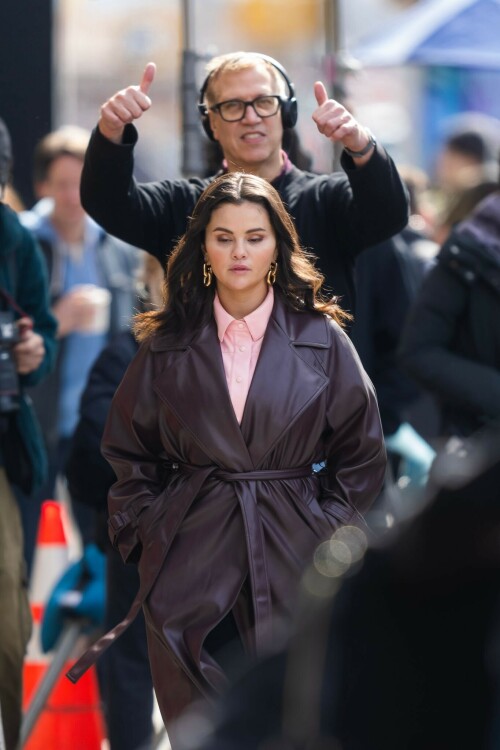 Selena Gomez On The Set in NYC - March 17 2023

Selena Gomez - ''Only Murderers in the Building'' set, NYC - March 17, 2023

Selena Gomez Wears Chic Oversized Plum Coat On 'Only Murders In the Building' Set

On Friday morning, Selena Gomez was photographed on the set of her hit Hulu show Only Murders In The Building in Queens, NY, with her co-stars Steve Martin and Martin Short. The singer and actress' look for the day included black denim pants peeking out from under an oversized dark purple trench coat by Olēnich. The statement piece made from faux leather featured large lapels and a belt cinching her in at the waist.

Under the coat was a pale pink button down and on her feet were a pair of white lace-up boots with a thick black sole.

Gomez left her long brunette hair down in waves and wore a pair of gold double hoop earrings. She had on a natural makeup palette for the shoot with a light coral lip.

On Only Murders in the Building, Gomez plays Mabel Mora, one of a trio of friends who are obsessed with true crime and who start a podcast together as they investigate a murder in their own apartment building. The show was renewed for a third season after receiving much critical acclaim, and has attracted lots of big guest stars like Tina Fey, Ryan Broussard, Jane Lynch, Meryl Streep, Ashley Park, and Paul Rudd.

The pop star told Deadline in an interview last year that when she was pitched the role, she was immediately excited to work with Martin and Short — and that the show's subject was of personal interest to her.

“They pitched me the idea and it led into a whole conversation about my actual obsession with true crime,” said Gomez. “I had just come back from CrimeCon when I had the call and it just felt like it was something I really wanted to do. They were all so lovely. And working with Steve and Marty would be a dream.”

ELLE/AIMÉE LUTKIN