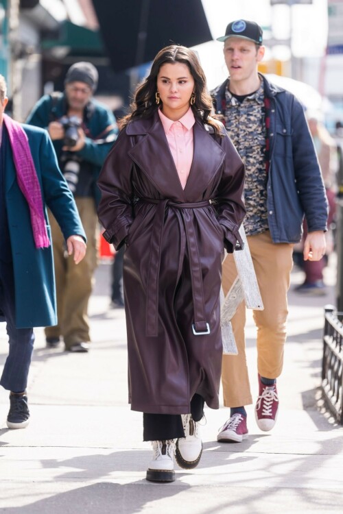 Selena Gomez On The Set in NYC - March 17 2023

Selena Gomez - ''Only Murderers in the Building'' set, NYC - March 17, 2023

Selena Gomez Wears Chic Oversized Plum Coat On 'Only Murders In the Building' Set

On Friday morning, Selena Gomez was photographed on the set of her hit Hulu show Only Murders In The Building in Queens, NY, with her co-stars Steve Martin and Martin Short. The singer and actress' look for the day included black denim pants peeking out from under an oversized dark purple trench coat by Olēnich. The statement piece made from faux leather featured large lapels and a belt cinching her in at the waist.

Under the coat was a pale pink button down and on her feet were a pair of white lace-up boots with a thick black sole.

Gomez left her long brunette hair down in waves and wore a pair of gold double hoop earrings. She had on a natural makeup palette for the shoot with a light coral lip.

On Only Murders in the Building, Gomez plays Mabel Mora, one of a trio of friends who are obsessed with true crime and who start a podcast together as they investigate a murder in their own apartment building. The show was renewed for a third season after receiving much critical acclaim, and has attracted lots of big guest stars like Tina Fey, Ryan Broussard, Jane Lynch, Meryl Streep, Ashley Park, and Paul Rudd.

The pop star told Deadline in an interview last year that when she was pitched the role, she was immediately excited to work with Martin and Short — and that the show's subject was of personal interest to her.

“They pitched me the idea and it led into a whole conversation about my actual obsession with true crime,” said Gomez. “I had just come back from CrimeCon when I had the call and it just felt like it was something I really wanted to do. They were all so lovely. And working with Steve and Marty would be a dream.”

ELLE/AIMÉE LUTKIN