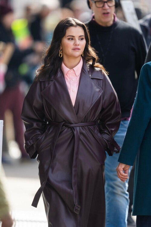 Selena Gomez On The Set in NYC - March 17 2023

Selena Gomez - ''Only Murderers in the Building'' set, NYC - March 17, 2023

Selena Gomez Wears Chic Oversized Plum Coat On 'Only Murders In the Building' Set

On Friday morning, Selena Gomez was photographed on the set of her hit Hulu show Only Murders In The Building in Queens, NY, with her co-stars Steve Martin and Martin Short. The singer and actress' look for the day included black denim pants peeking out from under an oversized dark purple trench coat by Olēnich. The statement piece made from faux leather featured large lapels and a belt cinching her in at the waist.

Under the coat was a pale pink button down and on her feet were a pair of white lace-up boots with a thick black sole.

Gomez left her long brunette hair down in waves and wore a pair of gold double hoop earrings. She had on a natural makeup palette for the shoot with a light coral lip.

On Only Murders in the Building, Gomez plays Mabel Mora, one of a trio of friends who are obsessed with true crime and who start a podcast together as they investigate a murder in their own apartment building. The show was renewed for a third season after receiving much critical acclaim, and has attracted lots of big guest stars like Tina Fey, Ryan Broussard, Jane Lynch, Meryl Streep, Ashley Park, and Paul Rudd.

The pop star told Deadline in an interview last year that when she was pitched the role, she was immediately excited to work with Martin and Short — and that the show's subject was of personal interest to her.

“They pitched me the idea and it led into a whole conversation about my actual obsession with true crime,” said Gomez. “I had just come back from CrimeCon when I had the call and it just felt like it was something I really wanted to do. They were all so lovely. And working with Steve and Marty would be a dream.”

ELLE/AIMÉE LUTKIN