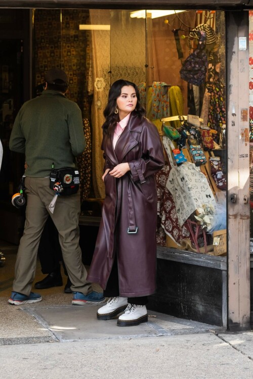 Selena Gomez - ''Only Murderers in the Building'' set, NYC - March 17, 2023

Selena Gomez Wears Chic Oversized Plum Coat On 'Only Murders In the Building' Set

On Friday morning, Selena Gomez was photographed on the set of her hit Hulu show Only Murders In The Building in Queens, NY, with her co-stars Steve Martin and Martin Short. The singer and actress' look for the day included black denim pants peeking out from under an oversized dark purple trench coat by Olēnich. The statement piece made from faux leather featured large lapels and a belt cinching her in at the waist.

Under the coat was a pale pink button down and on her feet were a pair of white lace-up boots with a thick black sole.

Gomez left her long brunette hair down in waves and wore a pair of gold double hoop earrings. She had on a natural makeup palette for the shoot with a light coral lip.

On Only Murders in the Building, Gomez plays Mabel Mora, one of a trio of friends who are obsessed with true crime and who start a podcast together as they investigate a murder in their own apartment building. The show was renewed for a third season after receiving much critical acclaim, and has attracted lots of big guest stars like Tina Fey, Ryan Broussard, Jane Lynch, Meryl Streep, Ashley Park, and Paul Rudd.

The pop star told Deadline in an interview last year that when she was pitched the role, she was immediately excited to work with Martin and Short — and that the show's subject was of personal interest to her.

“They pitched me the idea and it led into a whole conversation about my actual obsession with true crime,” said Gomez. “I had just come back from CrimeCon when I had the call and it just felt like it was something I really wanted to do. They were all so lovely. And working with Steve and Marty would be a dream.”

ELLE/AIMÉE LUTKIN