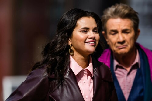 Selena Gomez On The Set in NYC - March 17 2023

Selena Gomez - ''Only Murderers in the Building'' set, NYC - March 17, 2023

Selena Gomez Wears Chic Oversized Plum Coat On 'Only Murders In the Building' Set

On Friday morning, Selena Gomez was photographed on the set of her hit Hulu show Only Murders In The Building in Queens, NY, with her co-stars Steve Martin and Martin Short. The singer and actress' look for the day included black denim pants peeking out from under an oversized dark purple trench coat by Olēnich. The statement piece made from faux leather featured large lapels and a belt cinching her in at the waist.

Under the coat was a pale pink button down and on her feet were a pair of white lace-up boots with a thick black sole.

Gomez left her long brunette hair down in waves and wore a pair of gold double hoop earrings. She had on a natural makeup palette for the shoot with a light coral lip.

On Only Murders in the Building, Gomez plays Mabel Mora, one of a trio of friends who are obsessed with true crime and who start a podcast together as they investigate a murder in their own apartment building. The show was renewed for a third season after receiving much critical acclaim, and has attracted lots of big guest stars like Tina Fey, Ryan Broussard, Jane Lynch, Meryl Streep, Ashley Park, and Paul Rudd.

The pop star told Deadline in an interview last year that when she was pitched the role, she was immediately excited to work with Martin and Short — and that the show's subject was of personal interest to her.

“They pitched me the idea and it led into a whole conversation about my actual obsession with true crime,” said Gomez. “I had just come back from CrimeCon when I had the call and it just felt like it was something I really wanted to do. They were all so lovely. And working with Steve and Marty would be a dream.”

ELLE/AIMÉE LUTKIN