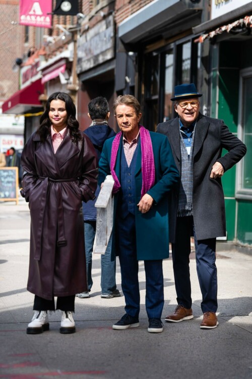 Selena Gomez - ''Only Murderers in the Building'' set, NYC - March 17, 2023

Selena Gomez Wears Chic Oversized Plum Coat On 'Only Murders In the Building' Set

On Friday morning, Selena Gomez was photographed on the set of her hit Hulu show Only Murders In The Building in Queens, NY, with her co-stars Steve Martin and Martin Short. The singer and actress' look for the day included black denim pants peeking out from under an oversized dark purple trench coat by Olēnich. The statement piece made from faux leather featured large lapels and a belt cinching her in at the waist.

Under the coat was a pale pink button down and on her feet were a pair of white lace-up boots with a thick black sole.

Gomez left her long brunette hair down in waves and wore a pair of gold double hoop earrings. She had on a natural makeup palette for the shoot with a light coral lip.

On Only Murders in the Building, Gomez plays Mabel Mora, one of a trio of friends who are obsessed with true crime and who start a podcast together as they investigate a murder in their own apartment building. The show was renewed for a third season after receiving much critical acclaim, and has attracted lots of big guest stars like Tina Fey, Ryan Broussard, Jane Lynch, Meryl Streep, Ashley Park, and Paul Rudd.

The pop star told Deadline in an interview last year that when she was pitched the role, she was immediately excited to work with Martin and Short — and that the show's subject was of personal interest to her.

“They pitched me the idea and it led into a whole conversation about my actual obsession with true crime,” said Gomez. “I had just come back from CrimeCon when I had the call and it just felt like it was something I really wanted to do. They were all so lovely. And working with Steve and Marty would be a dream.”

ELLE/AIMÉE LUTKIN