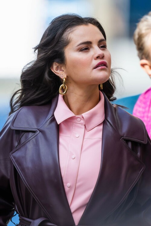 Selena Gomez On The Set in NYC - March 17 2023

Selena Gomez - ''Only Murderers in the Building'' set, NYC - March 17, 2023

Selena Gomez Wears Chic Oversized Plum Coat On 'Only Murders In the Building' Set

On Friday morning, Selena Gomez was photographed on the set of her hit Hulu show Only Murders In The Building in Queens, NY, with her co-stars Steve Martin and Martin Short. The singer and actress' look for the day included black denim pants peeking out from under an oversized dark purple trench coat by Olēnich. The statement piece made from faux leather featured large lapels and a belt cinching her in at the waist.

Under the coat was a pale pink button down and on her feet were a pair of white lace-up boots with a thick black sole.

Gomez left her long brunette hair down in waves and wore a pair of gold double hoop earrings. She had on a natural makeup palette for the shoot with a light coral lip.

On Only Murders in the Building, Gomez plays Mabel Mora, one of a trio of friends who are obsessed with true crime and who start a podcast together as they investigate a murder in their own apartment building. The show was renewed for a third season after receiving much critical acclaim, and has attracted lots of big guest stars like Tina Fey, Ryan Broussard, Jane Lynch, Meryl Streep, Ashley Park, and Paul Rudd.

The pop star told Deadline in an interview last year that when she was pitched the role, she was immediately excited to work with Martin and Short — and that the show's subject was of personal interest to her.

“They pitched me the idea and it led into a whole conversation about my actual obsession with true crime,” said Gomez. “I had just come back from CrimeCon when I had the call and it just felt like it was something I really wanted to do. They were all so lovely. And working with Steve and Marty would be a dream.”

ELLE/AIMÉE LUTKIN