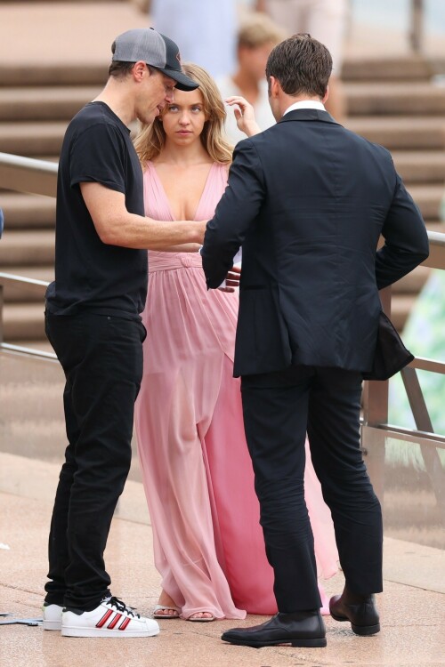 Sydney Sweeney with Glen Powell filming scenes for their upcoming untitled film in Sydney, Australia - March 27 2023

Sydney Sweeney Embraces Rom-Com Dressing in Flowy Pink Dress & Sparkling Sandals While Filming With Glen Powell in Australia

Sydney Sweeney was seen on Monday at the steps of the Sydney Opera House in Sydney, filming for her unnamed upcoming rom-com alongside leading man Glen Powell.

Sweeney and Powell were seen on the steps of the well-known performance center in rom-com-ready ensembles. Powell, who has previously starred in romantic features like “Set It Up,” wore a classic black-and-white tuxedo with black leather point-toe oxfords.

Whereas Sweeney looked every bit the leading lady in a flowing, deeply-cut, deftly-wrapped pink gown with a gauzy overlay of fabric over the skirt. The actress wore her well-known blond locks in a center part and styled them into soft, romantic waves.

For shoes, Sweeney donned a pair of peep-toe silver stiletto heels. The style featured a glittery finish and a ankle-strap for extra security.

When she’s not on set, Sweeney can be seen rocking a variety of footwear styles from ladylike mules to sky-high stilettos. She has been seen wearing a variety of designers, from Jimmy Choo to Tory Burch. Sweeney has been a Tory Burch brand ambassador since Apr. 2022, notably starring in the designer’s summer 2022 campaign, highlighting her popular Miller sandal line.

Sweeney has gained worldwide recognition after playing the love-obsessed Cassie on the hit HBO series “Euphoria”, and in the past year has been stepping into a variety of roles outside of the dramatic high school archetype.

On Jan. 11, Deadline reported that Sweeney and Powell signed on to star in a to-be-named rated-R romantic comedy film directed by Will Gluck. Not only is Sweeney the leading lady of the film, but she is also serving as the project’s executive producer.