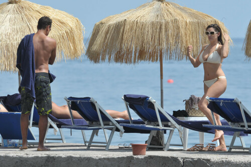 Kelly Brook - White Bikini Candids - Ischia, Italy - July 14, 2011

Ciao bella! Kelly Brook looks just creamy in a pale bikini as she takes a cooling dip on holiday in the Bay Of Naples

She's been having fun in the Italian sun after hitting the Ischia Film Festival to boost her profile as an actress - and now Kelly Brook has revealed the figure that her fans know and love on the beach.

The curvy 31-year-old stripped down to a cream bikini at her hotel to top up her tan with a friend and have a refreshing swim in the Tyrrhenian Sea.

The stunning model is having a few days off now the festival has finished and today decided to relax by the pool at her hotel on the island of Ischia after a day trip across the bay to Naples yesterday.

Kelly is staying at the L'Albergo Della Regina Isabella on the island in the Bay Of Naples and chose to have a dip in one of the hotel's three pools.

She also larked about with a friend and took a picture of the two of them together

Built on ancient Greek-Roman ruins on the seashore, it was built in the Dolce Vita era of the 1950s.

Kelly will also be looking forward to the live music in the cocktail bar every evening.

However, Kelly's boyfriend Thom won't be joining her.

Her spokesman told Mail Online: 'She's gone out with her U.S. agent but will back at the weekend and no, Thom isn't joining her as it's a quick trip.'

Yesterday, Kelly's smile was almost as sunny as the weather yesterday as the star enjoyed a day trip to Naples across the water.

She turned tourist as she strolled the streets of old Napoli before taking to the waves on a boat trip.

The beaming star was wearing a gorgeous 1950s-style sundress from the Jasper Conran Spring/Summer 2011 collection with a cute seaside print and had teamed it with cute lemon yellow Superga plimsolls with white soles and a chic Louis Vuitton handbag.

Kelly flew out earlier this week to the island of Ischia, which is in the Bay Of Naples, for the annual film festival.

However, there's been no sign of her hunky boyfriend Thom Evans as yet.

Kelly is certainly enjoying herself regardless.

She wrote on her Twitter in the early hours of this morning: 'Just took a boat ride home under a full moon with beautiful people. Viva Italia'.

Fans of Kelly - and probably a lot of those Italian men - will be hoping that Kelly pays a visit to the beach while she's there.

The model has teamed up with New Look to launch a swimwear range which has proved popular with stars of The Only Way Is Essex.

Kelly could use her holiday as a chance to model her own pieces while topping up her tan at the same time.

DailyMail