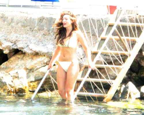 Kelly Brook - White Bikini Candids - Ischia, Italy - July 14, 2011

Ciao bella! Kelly Brook looks just creamy in a pale bikini as she takes a cooling dip on holiday in the Bay Of Naples

She's been having fun in the Italian sun after hitting the Ischia Film Festival to boost her profile as an actress - and now Kelly Brook has revealed the figure that her fans know and love on the beach.

The curvy 31-year-old stripped down to a cream bikini at her hotel to top up her tan with a friend and have a refreshing swim in the Tyrrhenian Sea.

The stunning model is having a few days off now the festival has finished and today decided to relax by the pool at her hotel on the island of Ischia after a day trip across the bay to Naples yesterday.

Kelly is staying at the L'Albergo Della Regina Isabella on the island in the Bay Of Naples and chose to have a dip in one of the hotel's three pools.

She also larked about with a friend and took a picture of the two of them together

Built on ancient Greek-Roman ruins on the seashore, it was built in the Dolce Vita era of the 1950s.

Kelly will also be looking forward to the live music in the cocktail bar every evening.

However, Kelly's boyfriend Thom won't be joining her.

Her spokesman told Mail Online: 'She's gone out with her U.S. agent but will back at the weekend and no, Thom isn't joining her as it's a quick trip.'

Yesterday, Kelly's smile was almost as sunny as the weather yesterday as the star enjoyed a day trip to Naples across the water.

She turned tourist as she strolled the streets of old Napoli before taking to the waves on a boat trip.

The beaming star was wearing a gorgeous 1950s-style sundress from the Jasper Conran Spring/Summer 2011 collection with a cute seaside print and had teamed it with cute lemon yellow Superga plimsolls with white soles and a chic Louis Vuitton handbag.

Kelly flew out earlier this week to the island of Ischia, which is in the Bay Of Naples, for the annual film festival.

However, there's been no sign of her hunky boyfriend Thom Evans as yet.

Kelly is certainly enjoying herself regardless.

She wrote on her Twitter in the early hours of this morning: 'Just took a boat ride home under a full moon with beautiful people. Viva Italia'.

Fans of Kelly - and probably a lot of those Italian men - will be hoping that Kelly pays a visit to the beach while she's there.

The model has teamed up with New Look to launch a swimwear range which has proved popular with stars of The Only Way Is Essex.

Kelly could use her holiday as a chance to model her own pieces while topping up her tan at the same time.

DailyMail