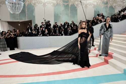 Met Gala 2023: Rita Ora Is Serving Fashion Witch at The Met Gala

May shmay! It's spooky season for Rita.

Fifty Shades of Grey actor Rita Ora arrived at the 2023 Met Gala in a witchy and bewitching gown that makes us feel incredibly October given that it's May. Is she vying for a part on her beau Taika Waititi's What We Do in the Shadows? Very much still in her boudoir fashion era. It's not not lingerie.

Ora's Prabal Gurung gown for the event plays with sheer and with layers, two elements she's been wearing a lot lately, but it's the nails and train that really stand out. Her long black…cloak? Cape? Scarf? covered nearly the length of the blue, white, and red carpet, creating a dramatic silhouette and, frankly, giving her a moment to get all camera lenses on her.

Equally decadent were the jewels literally dripping from her fingertips, as glittering ropes cascaded from her nails. Okay but like, how's she gonna eat dinner inside?

The smoky eye will never die. But combined with the lined lips? It's the new classics.

Ora reflected on the night's theme—"Karl Lagerfeld: A Line of Beauty"—on Instagram, sharing two posts in honor of the late designer. In the first, she and Lagerfeld pose together at various events, she walks the runway in a silver ensemble, and wears his designs for Chanel in various shoots.

In the second photo roundup, seemingly taken recently (peep the nails), Ora plays around in an old costume made by Karl himself. "In memory of Karl I had to bring back this custom piece he made me for a Chanel show performance I did with him in Monaco back in 2013. See you tomorrow!!" the singer wrote.

It's not that this doesn't go with the theme—the flowers and the black are totally Lagerfeldian—but anyone else think this is what she would have worn no matter what?

Rita Ora attends The 2023 Met Gala Celebrating "Karl Lagerfeld: A Line Of Beauty" at The Metropolitan Museum of Art on May 01, 2023 in New York City.

Met Gala 2023: Rita Ora sizzles in a black sheer gown as she joins dapper husband Taika Waititi on the star-studded red carpet.

Rita Ora brought the goth glamour to the Met Gala 2023 red carpet with a sheer corseted gown by Prabal Gurung.

#RitaOra #2023MetGala