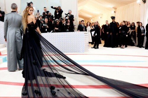 Rita Ora Makes a Case for Sheer on Met Gala Red Carpet 2023 in Prabal Gurung Dress & Strappy Sandals With Taika Waititi

Rita Ora arrived at the 2023 Met Gala in New York wearing an all-black ensemble. The singer posed on the carpet with her husband, director Taika Waititi.

Ora donned a daring outfit that featured detailed draping, striking cutouts and well-defined boning from Prabal Gurung.

The Nepalese-American fashion designer has been a fixture at the Met Gala since 2010. His designs have graced the red carpet, showcasing his signature style that often combines traditional Nepalese influences with modern, edgy elements. He has dressed a range of celebrities, from Sarah Jessica Parker to Zendaya over the years.

Regarding her footwear choice, Ora strapped on a pair of strappy sandals with a generous platform. These strappy platform sandals feature a chic ankle buckle closure that provides a secure fit. The almond toe design adds a touch of elegance, while the 6-inch heel elongates the legs and creates a flattering silhouette.

Ora’s fashion style is a mix of edgy and glamorous, often pushing boundaries with bold statement pieces. She is known for wearing daring outfits that showcase her confident and daring personality. Rita has also been a standout at the Met Gala, consistently impressing with her unique and avant-garde choices. From her bold silver feathered gown in 2016 to her Prada moment in 2021, she always manages to turn heads on the red carpet.

The Met Gala raises funds for the Metropolitan Museum of Art in New York City and celebrates the Costume Institute’s annual exhibits. This year’s theme, “Karl Lagerfeld: A Line of Beauty,” celebrates the life and career of designer Karl Lagerfeld. The 2023 event is notably co-chaired by Dua Lipa, Roger Federer, Michaela Coel, Penelope Cruz and Vogue editor-in-chief Anna Wintour.

Rita Ora attends The 2023 Met Gala Celebrating "Karl Lagerfeld: A Line Of Beauty" at The Metropolitan Museum of Art on May 01, 2023 in New York City.

Met Gala 2023: Rita Ora sizzles in a black sheer gown as she joins dapper husband Taika Waititi on the star-studded red carpet.

Rita Ora brought the goth glamour to the Met Gala 2023 red carpet with a sheer corseted gown by Prabal Gurung.

#RitaOra #2023MetGala