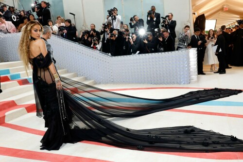 Met Gala 2023: Rita Ora Is Serving Fashion Witch at The Met Gala

May shmay! It's spooky season for Rita.

Fifty Shades of Grey actor Rita Ora arrived at the 2023 Met Gala in a witchy and bewitching gown that makes us feel incredibly October given that it's May. Is she vying for a part on her beau Taika Waititi's What We Do in the Shadows? Very much still in her boudoir fashion era. It's not not lingerie.

Ora's Prabal Gurung gown for the event plays with sheer and with layers, two elements she's been wearing a lot lately, but it's the nails and train that really stand out. Her long black…cloak? Cape? Scarf? covered nearly the length of the blue, white, and red carpet, creating a dramatic silhouette and, frankly, giving her a moment to get all camera lenses on her.

Equally decadent were the jewels literally dripping from her fingertips, as glittering ropes cascaded from her nails. Okay but like, how's she gonna eat dinner inside?

The smoky eye will never die. But combined with the lined lips? It's the new classics.

Ora reflected on the night's theme—"Karl Lagerfeld: A Line of Beauty"—on Instagram, sharing two posts in honor of the late designer. In the first, she and Lagerfeld pose together at various events, she walks the runway in a silver ensemble, and wears his designs for Chanel in various shoots.

In the second photo roundup, seemingly taken recently (peep the nails), Ora plays around in an old costume made by Karl himself. "In memory of Karl I had to bring back this custom piece he made me for a Chanel show performance I did with him in Monaco back in 2013. See you tomorrow!!" the singer wrote.

It's not that this doesn't go with the theme—the flowers and the black are totally Lagerfeldian—but anyone else think this is what she would have worn no matter what?

Rita Ora attends The 2023 Met Gala Celebrating "Karl Lagerfeld: A Line Of Beauty" at The Metropolitan Museum of Art on May 01, 2023 in New York City.

Met Gala 2023: Rita Ora sizzles in a black sheer gown as she joins dapper husband Taika Waititi on the star-studded red carpet.

Rita Ora brought the goth glamour to the Met Gala 2023 red carpet with a sheer corseted gown by Prabal Gurung.

#RitaOra #2023MetGala