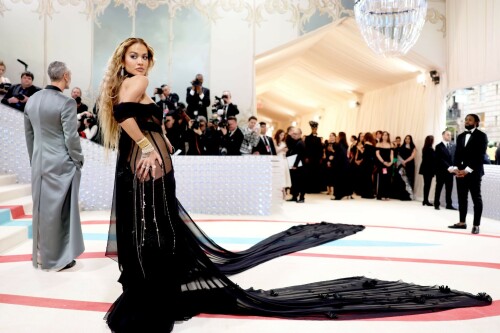 Met Gala 2023: Rita Ora Is Serving Fashion Witch at The Met Gala

May shmay! It's spooky season for Rita.

Fifty Shades of Grey actor Rita Ora arrived at the 2023 Met Gala in a witchy and bewitching gown that makes us feel incredibly October given that it's May. Is she vying for a part on her beau Taika Waititi's What We Do in the Shadows? Very much still in her boudoir fashion era. It's not not lingerie.

Ora's Prabal Gurung gown for the event plays with sheer and with layers, two elements she's been wearing a lot lately, but it's the nails and train that really stand out. Her long black…cloak? Cape? Scarf? covered nearly the length of the blue, white, and red carpet, creating a dramatic silhouette and, frankly, giving her a moment to get all camera lenses on her.

Equally decadent were the jewels literally dripping from her fingertips, as glittering ropes cascaded from her nails. Okay but like, how's she gonna eat dinner inside?

The smoky eye will never die. But combined with the lined lips? It's the new classics.

Ora reflected on the night's theme—"Karl Lagerfeld: A Line of Beauty"—on Instagram, sharing two posts in honor of the late designer. In the first, she and Lagerfeld pose together at various events, she walks the runway in a silver ensemble, and wears his designs for Chanel in various shoots.

In the second photo roundup, seemingly taken recently (peep the nails), Ora plays around in an old costume made by Karl himself. "In memory of Karl I had to bring back this custom piece he made me for a Chanel show performance I did with him in Monaco back in 2013. See you tomorrow!!" the singer wrote.

It's not that this doesn't go with the theme—the flowers and the black are totally Lagerfeldian—but anyone else think this is what she would have worn no matter what?

Rita Ora attends The 2023 Met Gala Celebrating "Karl Lagerfeld: A Line Of Beauty" at The Metropolitan Museum of Art on May 01, 2023 in New York City.

Met Gala 2023: Rita Ora sizzles in a black sheer gown as she joins dapper husband Taika Waititi on the star-studded red carpet.

Rita Ora brought the goth glamour to the Met Gala 2023 red carpet with a sheer corseted gown by Prabal Gurung.

#RitaOra #2023MetGala