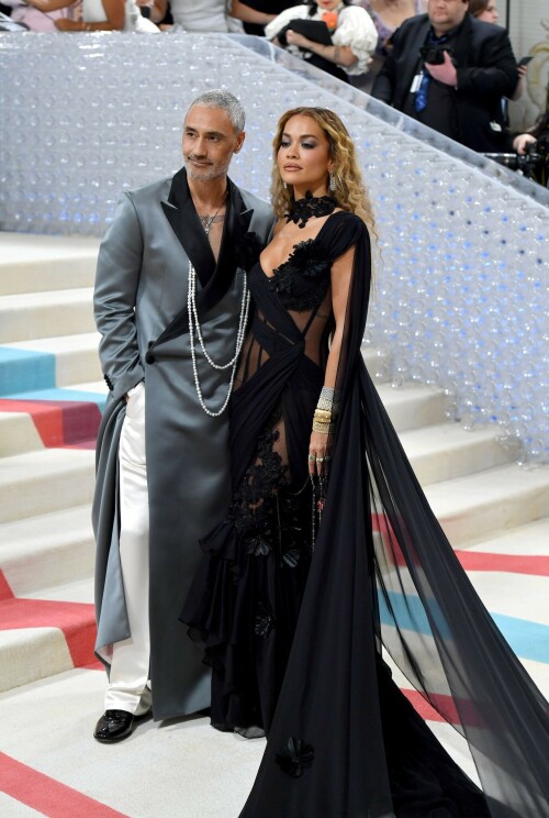 Rita Ora Makes a Case for Sheer on Met Gala Red Carpet 2023 in Prabal Gurung Dress & Strappy Sandals With Taika Waititi

Rita Ora arrived at the 2023 Met Gala in New York wearing an all-black ensemble. The singer posed on the carpet with her husband, director Taika Waititi.

Ora donned a daring outfit that featured detailed draping, striking cutouts and well-defined boning from Prabal Gurung.

The Nepalese-American fashion designer has been a fixture at the Met Gala since 2010. His designs have graced the red carpet, showcasing his signature style that often combines traditional Nepalese influences with modern, edgy elements. He has dressed a range of celebrities, from Sarah Jessica Parker to Zendaya over the years.

Regarding her footwear choice, Ora strapped on a pair of strappy sandals with a generous platform. These strappy platform sandals feature a chic ankle buckle closure that provides a secure fit. The almond toe design adds a touch of elegance, while the 6-inch heel elongates the legs and creates a flattering silhouette.

Ora’s fashion style is a mix of edgy and glamorous, often pushing boundaries with bold statement pieces. She is known for wearing daring outfits that showcase her confident and daring personality. Rita has also been a standout at the Met Gala, consistently impressing with her unique and avant-garde choices. From her bold silver feathered gown in 2016 to her Prada moment in 2021, she always manages to turn heads on the red carpet.

The Met Gala raises funds for the Metropolitan Museum of Art in New York City and celebrates the Costume Institute’s annual exhibits. This year’s theme, “Karl Lagerfeld: A Line of Beauty,” celebrates the life and career of designer Karl Lagerfeld. The 2023 event is notably co-chaired by Dua Lipa, Roger Federer, Michaela Coel, Penelope Cruz and Vogue editor-in-chief Anna Wintour.

Rita Ora attends The 2023 Met Gala Celebrating "Karl Lagerfeld: A Line Of Beauty" at The Metropolitan Museum of Art on May 01, 2023 in New York City.

Met Gala 2023: Rita Ora sizzles in a black sheer gown as she joins dapper husband Taika Waititi on the star-studded red carpet.

Rita Ora brought the goth glamour to the Met Gala 2023 red carpet with a sheer corseted gown by Prabal Gurung.

#RitaOra #2023MetGala