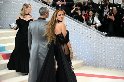 Met Gala 2023: Rita Ora Is Serving Fashion Witch at The Met Gala

May shmay! It's spooky season for Rita.

Fifty Shades of Grey actor Rita Ora arrived at the 2023 Met Gala in a witchy and bewitching gown that makes us feel incredibly October given that it's May. Is she vying for a part on her beau Taika Waititi's What We Do in the Shadows? Very much still in her boudoir fashion era. It's not not lingerie.

Ora's Prabal Gurung gown for the event plays with sheer and with layers, two elements she's been wearing a lot lately, but it's the nails and train that really stand out. Her long black…cloak? Cape? Scarf? covered nearly the length of the blue, white, and red carpet, creating a dramatic silhouette and, frankly, giving her a moment to get all camera lenses on her.

Equally decadent were the jewels literally dripping from her fingertips, as glittering ropes cascaded from her nails. Okay but like, how's she gonna eat dinner inside?

The smoky eye will never die. But combined with the lined lips? It's the new classics.

Ora reflected on the night's theme—"Karl Lagerfeld: A Line of Beauty"—on Instagram, sharing two posts in honor of the late designer. In the first, she and Lagerfeld pose together at various events, she walks the runway in a silver ensemble, and wears his designs for Chanel in various shoots.

In the second photo roundup, seemingly taken recently (peep the nails), Ora plays around in an old costume made by Karl himself. "In memory of Karl I had to bring back this custom piece he made me for a Chanel show performance I did with him in Monaco back in 2013. See you tomorrow!!" the singer wrote.

It's not that this doesn't go with the theme—the flowers and the black are totally Lagerfeldian—but anyone else think this is what she would have worn no matter what?

Rita Ora attends The 2023 Met Gala Celebrating "Karl Lagerfeld: A Line Of Beauty" at The Metropolitan Museum of Art on May 01, 2023 in New York City.

Met Gala 2023: Rita Ora sizzles in a black sheer gown as she joins dapper husband Taika Waititi on the star-studded red carpet.

Rita Ora brought the goth glamour to the Met Gala 2023 red carpet with a sheer corseted gown by Prabal Gurung.

#RitaOra #2023MetGala