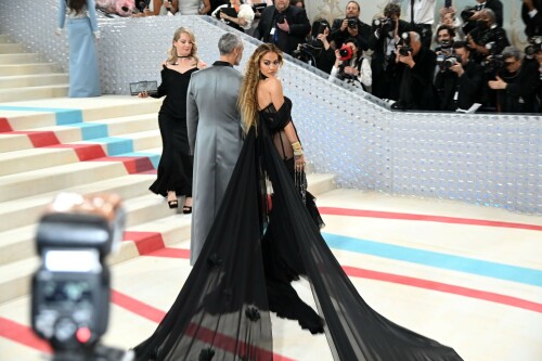 Met Gala 2023: Rita Ora Is Serving Fashion Witch at The Met Gala

May shmay! It's spooky season for Rita.

Fifty Shades of Grey actor Rita Ora arrived at the 2023 Met Gala in a witchy and bewitching gown that makes us feel incredibly October given that it's May. Is she vying for a part on her beau Taika Waititi's What We Do in the Shadows? Very much still in her boudoir fashion era. It's not not lingerie.

Ora's Prabal Gurung gown for the event plays with sheer and with layers, two elements she's been wearing a lot lately, but it's the nails and train that really stand out. Her long black…cloak? Cape? Scarf? covered nearly the length of the blue, white, and red carpet, creating a dramatic silhouette and, frankly, giving her a moment to get all camera lenses on her.

Equally decadent were the jewels literally dripping from her fingertips, as glittering ropes cascaded from her nails. Okay but like, how's she gonna eat dinner inside?

The smoky eye will never die. But combined with the lined lips? It's the new classics.

Ora reflected on the night's theme—"Karl Lagerfeld: A Line of Beauty"—on Instagram, sharing two posts in honor of the late designer. In the first, she and Lagerfeld pose together at various events, she walks the runway in a silver ensemble, and wears his designs for Chanel in various shoots.

In the second photo roundup, seemingly taken recently (peep the nails), Ora plays around in an old costume made by Karl himself. "In memory of Karl I had to bring back this custom piece he made me for a Chanel show performance I did with him in Monaco back in 2013. See you tomorrow!!" the singer wrote.

It's not that this doesn't go with the theme—the flowers and the black are totally Lagerfeldian—but anyone else think this is what she would have worn no matter what?

Rita Ora attends The 2023 Met Gala Celebrating "Karl Lagerfeld: A Line Of Beauty" at The Metropolitan Museum of Art on May 01, 2023 in New York City.

Met Gala 2023: Rita Ora sizzles in a black sheer gown as she joins dapper husband Taika Waititi on the star-studded red carpet.

Rita Ora brought the goth glamour to the Met Gala 2023 red carpet with a sheer corseted gown by Prabal Gurung.

#RitaOra #2023MetGala