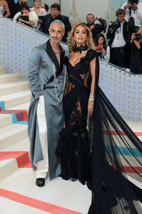 Rita Ora Makes a Case for Sheer on Met Gala Red Carpet 2023 in Prabal Gurung Dress & Strappy Sandals With Taika Waititi

Rita Ora arrived at the 2023 Met Gala in New York wearing an all-black ensemble. The singer posed on the carpet with her husband, director Taika Waititi.

Ora donned a daring outfit that featured detailed draping, striking cutouts and well-defined boning from Prabal Gurung.

The Nepalese-American fashion designer has been a fixture at the Met Gala since 2010. His designs have graced the red carpet, showcasing his signature style that often combines traditional Nepalese influences with modern, edgy elements. He has dressed a range of celebrities, from Sarah Jessica Parker to Zendaya over the years.

Regarding her footwear choice, Ora strapped on a pair of strappy sandals with a generous platform. These strappy platform sandals feature a chic ankle buckle closure that provides a secure fit. The almond toe design adds a touch of elegance, while the 6-inch heel elongates the legs and creates a flattering silhouette.

Ora’s fashion style is a mix of edgy and glamorous, often pushing boundaries with bold statement pieces. She is known for wearing daring outfits that showcase her confident and daring personality. Rita has also been a standout at the Met Gala, consistently impressing with her unique and avant-garde choices. From her bold silver feathered gown in 2016 to her Prada moment in 2021, she always manages to turn heads on the red carpet.

The Met Gala raises funds for the Metropolitan Museum of Art in New York City and celebrates the Costume Institute’s annual exhibits. This year’s theme, “Karl Lagerfeld: A Line of Beauty,” celebrates the life and career of designer Karl Lagerfeld. The 2023 event is notably co-chaired by Dua Lipa, Roger Federer, Michaela Coel, Penelope Cruz and Vogue editor-in-chief Anna Wintour.

Rita Ora attends The 2023 Met Gala Celebrating "Karl Lagerfeld: A Line Of Beauty" at The Metropolitan Museum of Art on May 01, 2023 in New York City.

Met Gala 2023: Rita Ora sizzles in a black sheer gown as she joins dapper husband Taika Waititi on the star-studded red carpet.

Rita Ora brought the goth glamour to the Met Gala 2023 red carpet with a sheer corseted gown by Prabal Gurung.

#RitaOra #2023MetGala