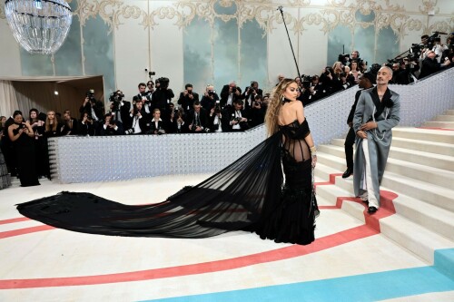 Rita Ora Makes a Case for Sheer on Met Gala Red Carpet 2023 in Prabal Gurung Dress & Strappy Sandals With Taika Waititi

Rita Ora arrived at the 2023 Met Gala in New York wearing an all-black ensemble. The singer posed on the carpet with her husband, director Taika Waititi.

Ora donned a daring outfit that featured detailed draping, striking cutouts and well-defined boning from Prabal Gurung.

The Nepalese-American fashion designer has been a fixture at the Met Gala since 2010. His designs have graced the red carpet, showcasing his signature style that often combines traditional Nepalese influences with modern, edgy elements. He has dressed a range of celebrities, from Sarah Jessica Parker to Zendaya over the years.

Regarding her footwear choice, Ora strapped on a pair of strappy sandals with a generous platform. These strappy platform sandals feature a chic ankle buckle closure that provides a secure fit. The almond toe design adds a touch of elegance, while the 6-inch heel elongates the legs and creates a flattering silhouette.

Ora’s fashion style is a mix of edgy and glamorous, often pushing boundaries with bold statement pieces. She is known for wearing daring outfits that showcase her confident and daring personality. Rita has also been a standout at the Met Gala, consistently impressing with her unique and avant-garde choices. From her bold silver feathered gown in 2016 to her Prada moment in 2021, she always manages to turn heads on the red carpet.

The Met Gala raises funds for the Metropolitan Museum of Art in New York City and celebrates the Costume Institute’s annual exhibits. This year’s theme, “Karl Lagerfeld: A Line of Beauty,” celebrates the life and career of designer Karl Lagerfeld. The 2023 event is notably co-chaired by Dua Lipa, Roger Federer, Michaela Coel, Penelope Cruz and Vogue editor-in-chief Anna Wintour.

Rita Ora attends The 2023 Met Gala Celebrating "Karl Lagerfeld: A Line Of Beauty" at The Metropolitan Museum of Art on May 01, 2023 in New York City.

Met Gala 2023: Rita Ora sizzles in a black sheer gown as she joins dapper husband Taika Waititi on the star-studded red carpet.

Rita Ora brought the goth glamour to the Met Gala 2023 red carpet with a sheer corseted gown by Prabal Gurung.

#RitaOra #2023MetGala