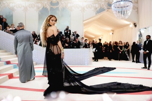 Met Gala 2023: Rita Ora Is Serving Fashion Witch at The Met Gala

May shmay! It's spooky season for Rita.

Fifty Shades of Grey actor Rita Ora arrived at the 2023 Met Gala in a witchy and bewitching gown that makes us feel incredibly October given that it's May. Is she vying for a part on her beau Taika Waititi's What We Do in the Shadows? Very much still in her boudoir fashion era. It's not not lingerie.

Ora's Prabal Gurung gown for the event plays with sheer and with layers, two elements she's been wearing a lot lately, but it's the nails and train that really stand out. Her long black…cloak? Cape? Scarf? covered nearly the length of the blue, white, and red carpet, creating a dramatic silhouette and, frankly, giving her a moment to get all camera lenses on her.

Equally decadent were the jewels literally dripping from her fingertips, as glittering ropes cascaded from her nails. Okay but like, how's she gonna eat dinner inside?

The smoky eye will never die. But combined with the lined lips? It's the new classics.

Ora reflected on the night's theme—"Karl Lagerfeld: A Line of Beauty"—on Instagram, sharing two posts in honor of the late designer. In the first, she and Lagerfeld pose together at various events, she walks the runway in a silver ensemble, and wears his designs for Chanel in various shoots.

In the second photo roundup, seemingly taken recently (peep the nails), Ora plays around in an old costume made by Karl himself. "In memory of Karl I had to bring back this custom piece he made me for a Chanel show performance I did with him in Monaco back in 2013. See you tomorrow!!" the singer wrote.

It's not that this doesn't go with the theme—the flowers and the black are totally Lagerfeldian—but anyone else think this is what she would have worn no matter what?

Rita Ora attends The 2023 Met Gala Celebrating "Karl Lagerfeld: A Line Of Beauty" at The Metropolitan Museum of Art on May 01, 2023 in New York City.

Met Gala 2023: Rita Ora sizzles in a black sheer gown as she joins dapper husband Taika Waititi on the star-studded red carpet.

Rita Ora brought the goth glamour to the Met Gala 2023 red carpet with a sheer corseted gown by Prabal Gurung.

#RitaOra #2023MetGala