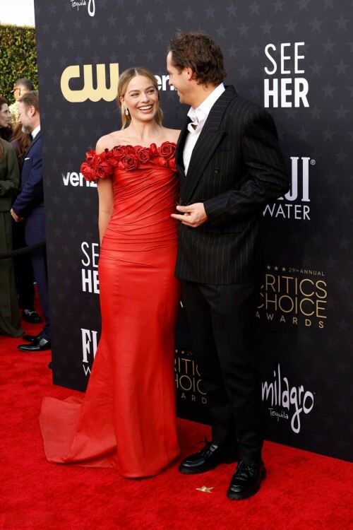 Margot Robbie | 29th Annual Critics Choice Awards in Santa Monica - 14.01.2024

Margot Robbie Brings Radiant Rose Barbie Alive in Red Balmain Dress at the Critics Choice Awards

Dua Lipa isn’t the only Barbie cast member to dress like a rose for the Critics Choice Awards. Best Actress nominee Margot Robbie attended the ceremony in her own rose-adorned look: a custom red Balmain column dress. She acessorized with Lorraine Schwartz jewelry. Her husband, Tom Ackerley, posed with her in a rare red carpet appearance for the couple. Fans speculated that she could be referencing 1996’s Radiant Rose Barbie with the outfit as the top part greatly resembles the Barbie’s red dress.

Barbie is up for 18 awards at the ceremony tonight. Robbie herself is up for Best Actress for her work in the film.

Robbie spoke to Deadline in a cover story released earlier this week about how they approached making a movie about Barbie given people’s different opinions about the doll.

She said:

We really didn’t want to avoid or appease anyone in particular. I feel that whenever characters or movies hit and feel successful, they’re holding up a mirror to the audience. Art is a way for us to understand ourselves: “By analyzing this character and their behavior, and the circumstances they’re in, I’m now able to make sense of something in my life.” That’s what I think every movie should strive to do, because you have to make it feel personal for the audience. You’ve got to make it resonate with them.

That’s not to say we all sat down trying to figure out the puzzle as you describe it. All I knew going into it was that there was an opportunity here to do that thing. It took a really smart person like Greta Gerwig to find the story, and figure out how to unpack all those things. I knew she wouldn’t be glossing over the spiky bits, which was important in our writer/director. I knew she wouldn’t be interested in doing that. She always wanted to explore both the good and the bad, because you don’t get a fully formed experience without looking at both.

But at the same time, and most important of all, it was about finding a person—and I always knew it should be Greta—who would be able to do it without mocking anything. Overall, it was important that it not be mean-spirited. It always had to come from a place of love. And I think it was about making it feel hopeful. It felt like we could hold the spiky bits and the warmth in the same hands.

At the end of the day, the movie is kind of not really about Barbie. Greta’s the genius that looked at it and went, “Aren’t humans so strange? They made a doll, then they got mad at the doll. That’s just insane.” And it’s true; we created Barbie and then we got mad at Barbie, because then we didn’t have to get mad at ourselves. We could shout at her; we could project onto her all of the perceived failings in the world, and we could direct the blame at her. It’s an inanimate object [laughs]. Isn’t that just so crazy?

I can’t claim any of these thoughts were fully fleshed out when I went after the rights for Barbie. But I knew someone would have those thoughts, and I recognized the opportunity and the kind of playground that someone smart like a Greta Gerwig could have fun in.

ELLE

#MargotRobbie