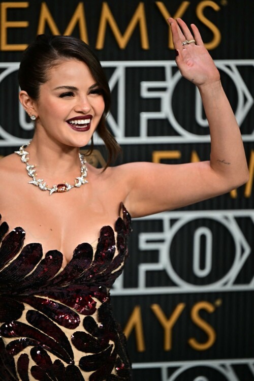 Selena Gomez | 75th Primetime Emmy Awards at the Peacock Theater in LA - 15.01.2024

Selena Gomez Shines on Emmys Red Carpet as Benny Blanco Blows Her a Kiss

Gomez looked glamorous in a custom Oscar de la Renta dress.

Selena Gomez, whose hit television series Only Murders in the Building is nominated for best comedy at the Emmy Awards, arrived on the red carpet with Benny Blanco Monday (Jan. 15).

While the the pair didn’t officially pose together, Blanco wasn’t far from Gomez’s side. As the pop star/actress stepped forward to be photographed, Blanco blew a kiss her way before walking away from the carpet.

Gomez looked glamorous in a formfitting, dark red Oscar de la Renta dress with a scalloped neckline and strappy black heels. The custom dress is made up of more than 450,000 pailletes and required 930 hours of hand embroidery, according to Oscar de la Renta. Her hair was swept back in an updo, with a loose, pretty wave grazing the side of her face, and her makeup featured a burgundy lip that complemented her elegant ensemble.

The Only Murders in the Building star first confirmed she and Blanco were an item on Dec. 7, half a year after the pair are believed to have started dating. She told fans in on Instagram that the producer is “my absolute everything in my heart” and that she’s at her “happiest” in the relationship.

Watch the couple’s sweet red carpet moment in a clip from E! below, and see them find their seats together in a video from The Hollywood Reporter. Plus, see a photo of Gomez’s full look, styled by Erin Walsh.

billboard

#SelenaGomez