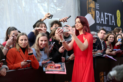 Dua Lipa at the EE BAFTA Film Awards 2024 at The Royal Festival Hall - 18.02.2024

Dua Lipa Wore a Statement-Making Red Gown and Cape on the 2024 BAFTA Awards Red Carpet

The only thing more fiery than the “Dance the Night” singer’s hair was her ensemble.

Dua Lipa certainly knows how to make a red carpet statement.

The "Levitating" singer walked the 2024 EE BAFTA Film Awards red carpet in a show-stopping floor-length red gown featuring a matching red cape that seemed to go on for miles.

The halterneck-pleated gown showed off Lipa's minimal arm tattoos and was free-flowing with a semi-cinched waist. The singer finished the look with minimal makeup that perfectly complimented not only her gown and semi-sheer cape but her purple and red fire-inspired hair.

Forever fashionable, Lipa's all-red ensemble continued the trend of all-red ensembles during the 2024 award season... and we certainly are here for it.

While silver looks were all the rage this year, more than a few A-list celebrities decided to go with an all-red look this awards season, especially during the 2024 Emmy Awards.

Suki Waterhouse, for example, co-signed the trend in a red Valentino gown featuring side cutouts that highlighted her pregnant belly.

Award-winning Succession star Sarah Snook also leaned into the trend during the Emmy Awards with a voluminous Vivienne Westwood ensemble that certainly honored Old Hollywood glam. The gown featured a corset-style bodice and sweeping skirt, and was paired with a stunning jewel necklace and diamond earrings.

While many celebrities have adopted the all-red trend this year, Lipa has certainly gone all-in with the addition of her fiery, cherry-red hair color.

Hairstylist Ben Gregory—who has helped Lipa play with her redhead looks—talked to Marie Claire exclusively about her updated, totally "in" look.

"We were having conversations about her new era and the next chapter. She was thinking about changing her hair," the UK-based hairstylist said. "The thing with Dua is that she’s such a beautiful, powerful-looking woman. She’s reminiscent in many ways of that old-school supermodel. They put her in the Chanel Claudia Schiffer gown for the Met, and there's a reason for that. She walks a line between being this fashion figure and a music artist for me. She has this old-school supermodel sexiness about her, but she’s also super young, contemporary, and cool."

marieclaire

#DuaLipa #BAFTAs